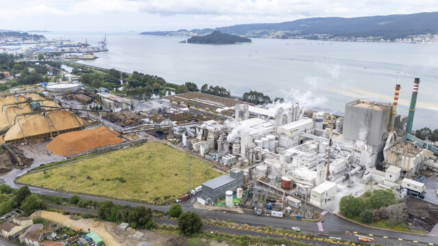 Aerial view of the Biofabrica de Ence pulp mill with its industrial structures and wood chip piles along the Ria de Pontevedra estuary, Pontevedra, Pontevedra, Spain.