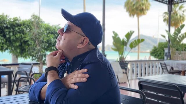 Hombre esperando solo en una terraza del paseo mar&iacute;timo