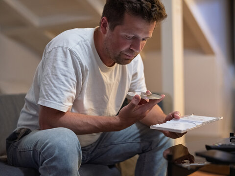 Man looking at a compact disc while sitting in a living room