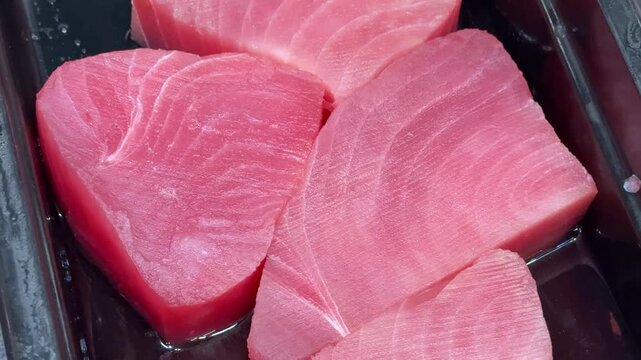 Small, young tunas, whole, with the head, chilled on shallow ice at the seafood market. An open shelf at the fish market. Close-up
