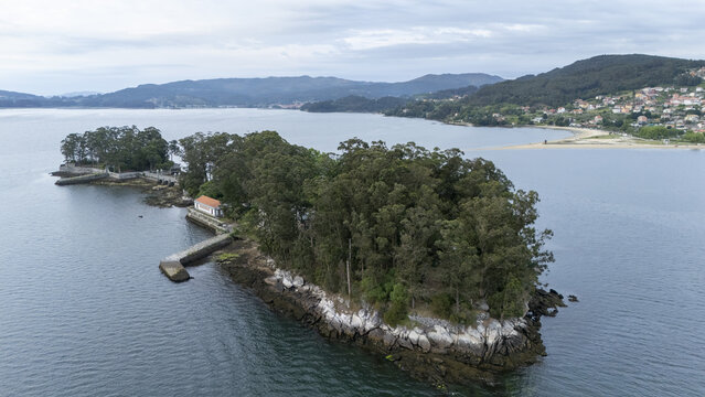 Aerial view of Illa de San Simon with its dense green trees, historic stone walls, and small buildings surrounded by the calm waters of the bay in Pontevedra, Pontevedra, Spain.