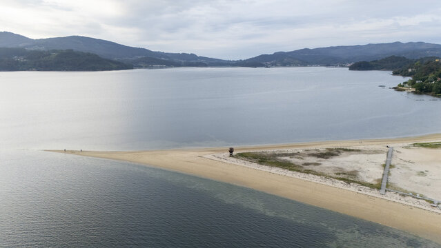 Aerial view of the Captain Nemo monument area on the sandy Cesantes beach spit surrounded by calm waters and green hills Vigo, Pontevedra, Spain.