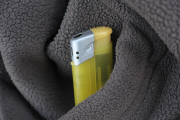 Close-up shows a yellow lighter hidden in gray fleece © jr-art