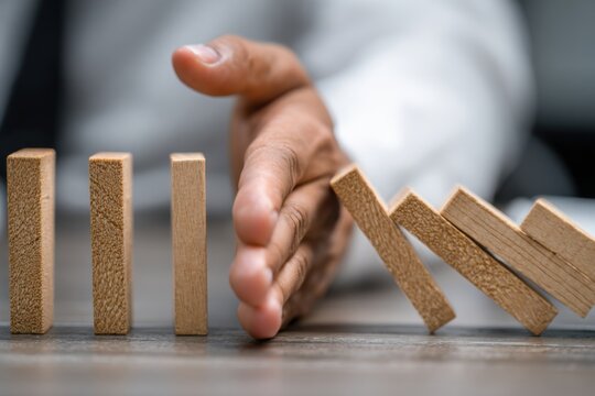 Business Hand Stopping Domino Effect Risk Management Strategy.
