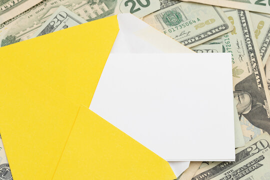 Blank greeting card in envelope over money