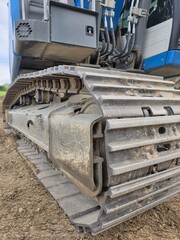 Close-up of a blue hydraulic excavator's tracked drive systems, emphasizing its rugged texture and intricate engineering.old rusty train © Yevhen