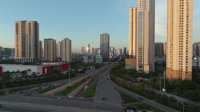 Drone aerial footage of modern residential towers and boulevard in Hanoi illuminated by soft morning sunlight.