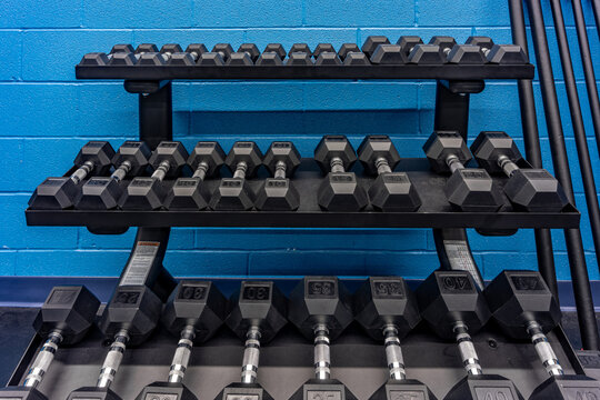 Organized three tier dumbbell rack with black hexagonal rubber weights with chrome handles.
