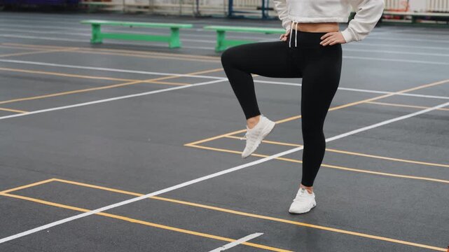 Badminton court footwork warmup white female athlete practicing precise knee lifts and balance on marked indoor court with ladder markers and coach nearby, focused intensity and steady rhythm
