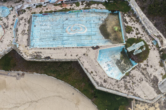 Aerial view of the abandoned swimming pool complex at Praia de Sao Pedro de Moel with graffiti and empty basins overlooking the beach in Marinha Grande, Leiria, Portugal.