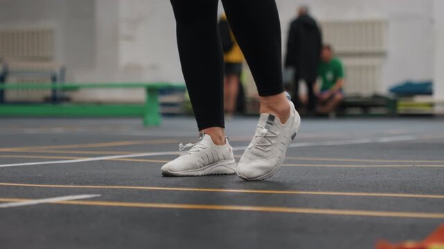 Instructor guides rapid agility drills using gym ribbons and court markings. Participants engage in focused badminton agility exercises with quick movements and precise footwork training