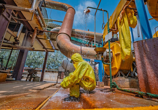 Male workers dressing in protective shower detoxification suit clean up after sealing a leaking container