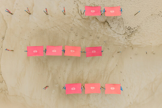 Aerial view of pink sunshades arranged in rows on the sandy beach of Praia de Sao Pedro de Moel Marinha Grande, Leiria, Portugal.