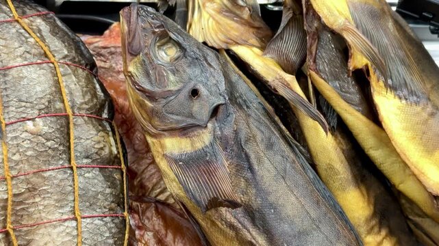 Cold smoked bream and walleye closeup, golden netting and textured scales on retail shelves, deli vendor arranging preserved fish