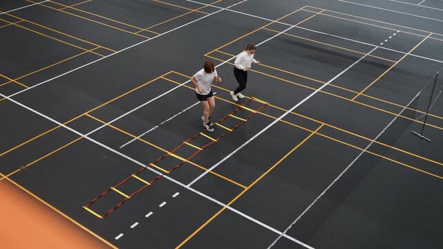 White teammates warming up on badminton court with ladder drill before match, club training environment with upbeat energy and focused drills, players practice timing rhythm and coordination