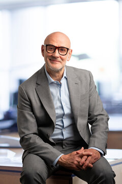 Portrait of a confident middle-aged bald businessman sitting at the office