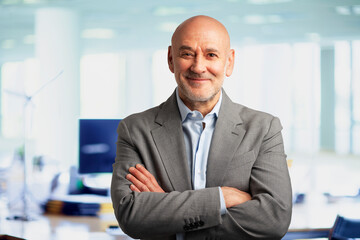 Fototapeta premium Portrait of a confident middle-aged bald businessman standing at the office