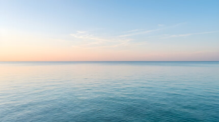 Obraz premium A serene and peaceful view of a calm ocean under a soft pastel sunset sky with gentle ripples on the water surface.