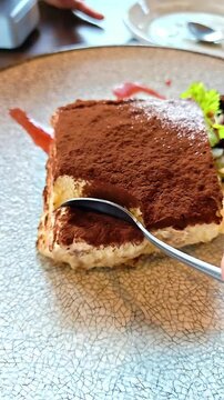 Spoon scooping up baked tiramisu with cocoa powder garnish, Italian Sponge Cake Confectionery, Cafe Dessert, Sweet Layered Bakery Dish
