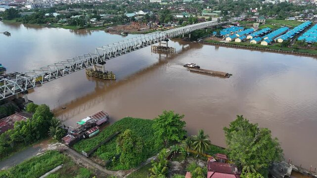 A view from atop the steel truss bridge spanning the Brown River along the urban riverfront with traffic in West Borneo, Indonesia.