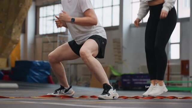 Partner plyometric badminton training session with lunges and explosive squats on indoor court, two athletes performing synchronized lower body drills to build power, stability, core engagement,