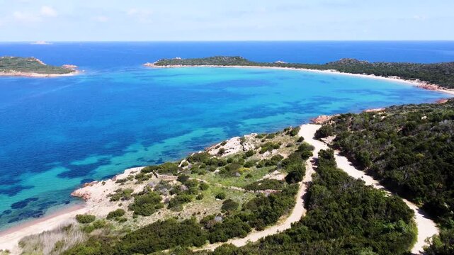 Forward drone flight over Capo Coda Cavallo in Sardinia with turquoise sea rocky coastline and Mediterranean landscape on a sunny day