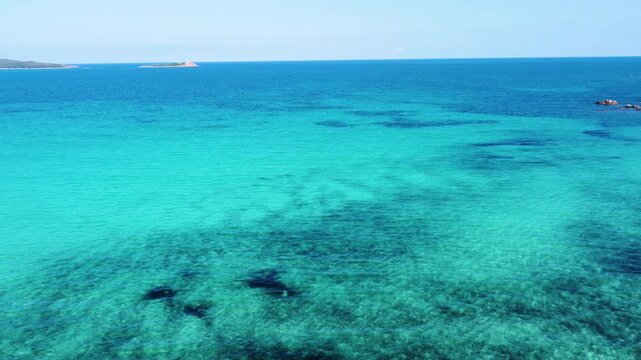 Aerial pull back view of Lu Impostu beach in Sardinia with turquoise water white sand and Mediterranean coastline on a sunny summer day