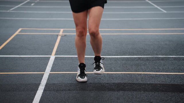 Court agility jump rope training legs, closeup of athlete legs completing lateral shuffles and vertical hops across painted lines on indoor badminton court, textured surface, quick foot changes, high