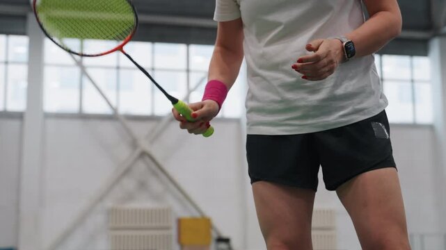 Repetitive indoor shuttle service emphasizing wrist snap and quick footwork. Player demonstrates consistent shuttle serving technique focusing on wrist movement and agility during training