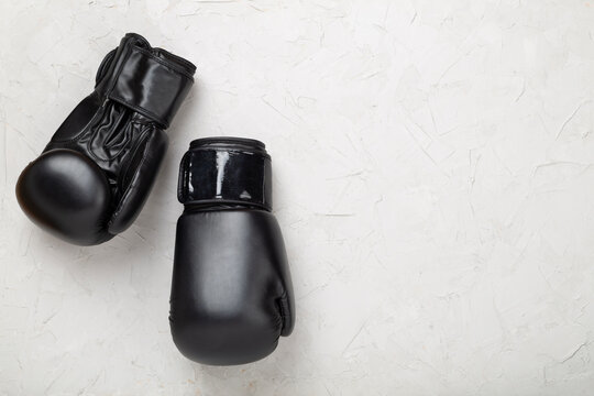 Black boxing gloves on concrete background, top view