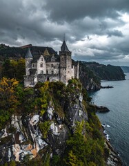 Fototapeta premium Majestic Castle on Cliff Overlooking Serene Ocean and Dramatic Sky