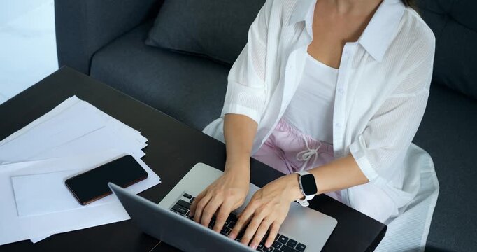 Professional woman concentrates on editing computer report documents. Dedicated woman types and edits reports amidst busy professional workspace filled with files and documentation