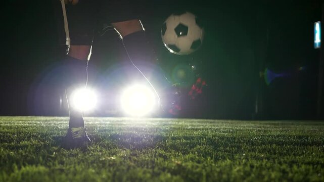 Male sports athlete playing soccer ball on the field at night