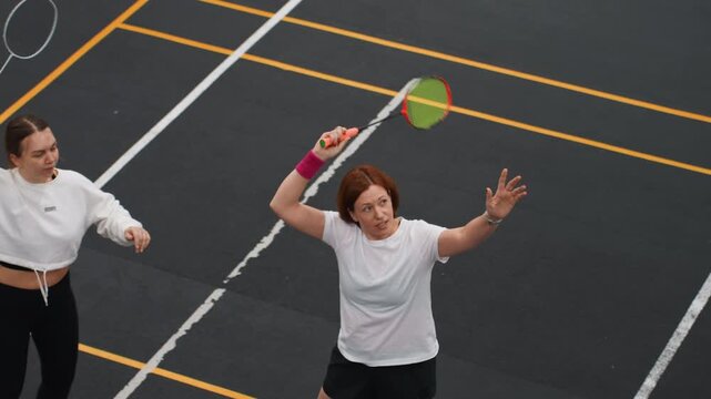 Focused woman improves badminton skills. Woman meticulously trains with badminton racket and court. Woman diligently hones her badminton techniques through targeted drills alone on marked court