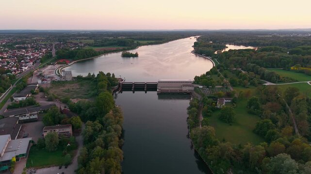 Aerial view of Donau Staustufe Ingolstadt shows dam, flowing river and surrounding forests. Warm light highlights the Stausee Ingolstadt and the balance of nature and water engineering in Bavaria.