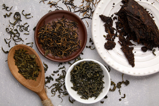 tea leaves of different varieties dried and fermented on a gray concrete table with a top view