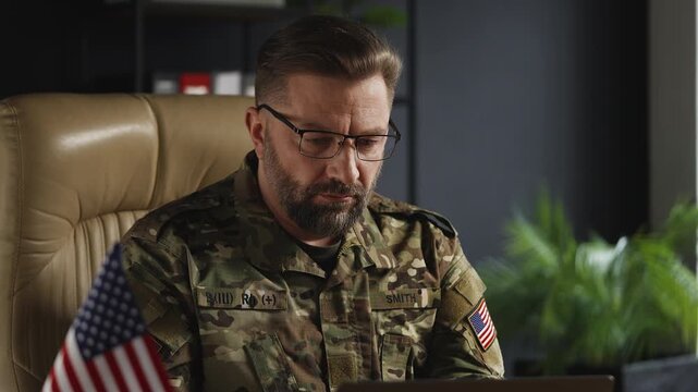 U.S. military officer working on laptop in office, assessing security strategy