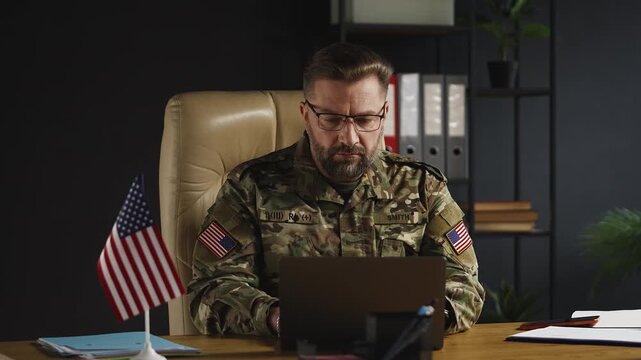 American army ranking officer typing on laptop, planning operations in office