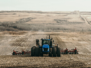 Fototapeta premium tractor pulling a seed drill and air seeder across a cultivated prairie field