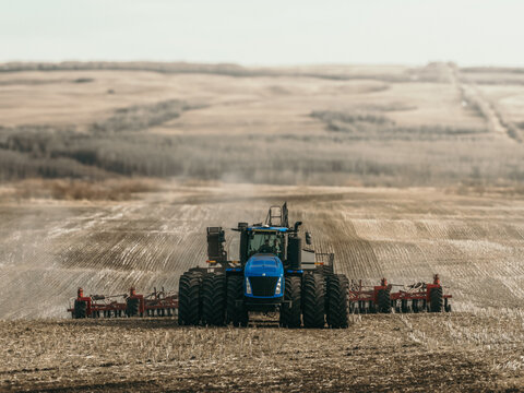 tractor pulling a seed drill and air seeder across a cultivated prairie field