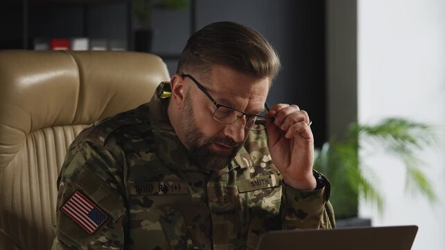 U.S. army officer overwhelmed with strategic decisions while working on laptop