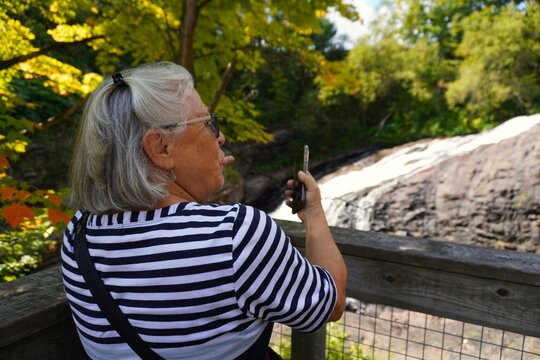 Senior woman taking a picture of kabir kouba fall in quebec, canada