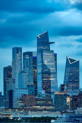 Fototapeten New York The illuminated skyscrapers of Midtown Manhattan glow against a deep blue twilight sky, showcasing the modern architectural design of the New York City skyline.  © Jose Luis Stephens