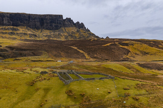 Aerial view of The Quiraing landscape with a historic stone sheepfold on rolling green hills under an overcast sky Isle of Skye, Scotland, United Kingdom.