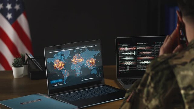 U.S. intelligence officer monitoring war zones on laptops while talking on phone