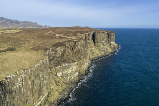 Aerial view of Kilt Rock and Mealt Falls with dramatic basalt columns and a waterfall plunging into the blue sea under a clear sky Isle of Skye, Scotland, United Kingdom.
