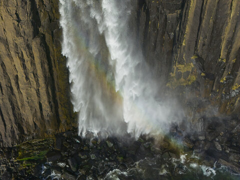 Aerial view of Kilt Rock and Mealt Falls cascading down basalt cliffs into the sea with a rainbow in the mist Isle of Skye, Scotland, United Kingdom.