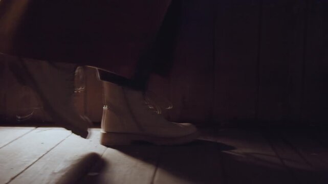Dim attic floor, boots step slowly warm square light spills through small window onto worn wooden planks closeup of white laceup boots beneath long cloak slow cautious movement, soft shadow, rustic