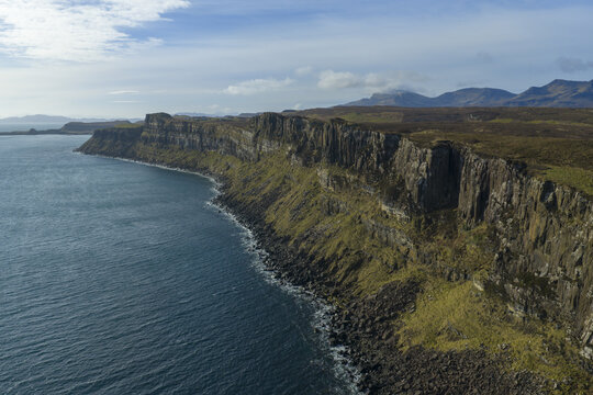 Aerial view of the dramatic basalt cliffs of Kilt Rock and Mealt Falls overlooking the blue ocean and distant mountains Isle of Skye, Scotland, United Kingdom.