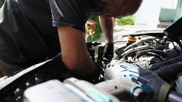 Professional mechanic repairing vehicle at workplace. Auto repairman removing radiator from automobile with tool outdoor. Male repairer making maintenance of car. Diagnostic transport concept